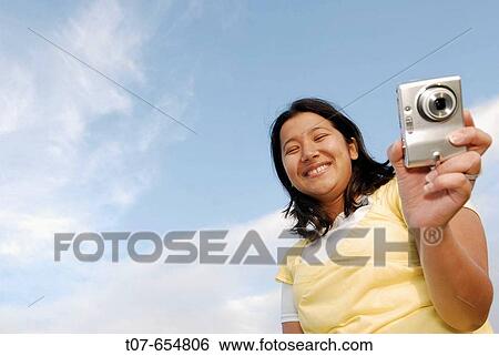 Latino woman holding digital camera. View Large Photo Image Stock Photograph - Latino woman holding digital camera.. Fotosearch