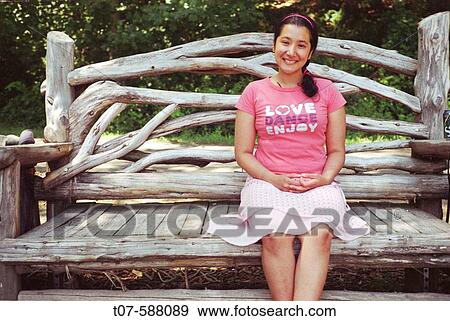Latino woman sitting on giant wooden chair. View Large Photo Image Stock Photo - Latino woman sitting on giant wooden chair.. Fotosearch
