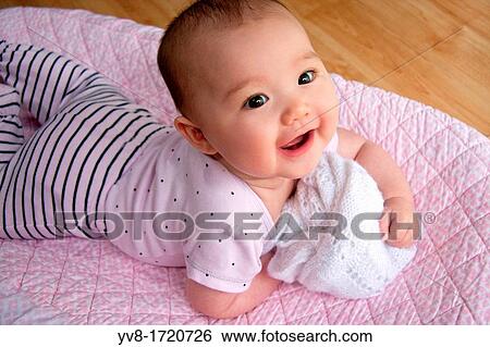 Stock Photograph - Laughing baby on her tummy. Fotosearch