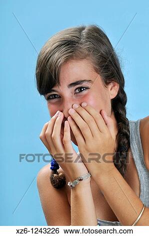 Stock Photograph - Laughing girl covers her facei, with blue backgroud. Fotosearch