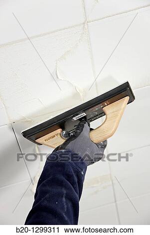 Stock Image - Laying tiles, glue mortar, using grout float, new homes under construction, construction site. Fotosearch