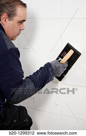 Laying tiles, glue mortar, using grout float, new homes under construction, construction site View Large Photo Image Stock Image - Laying tiles, glue mortar, using grout float, new homes under construction, construction site. Fotosearch