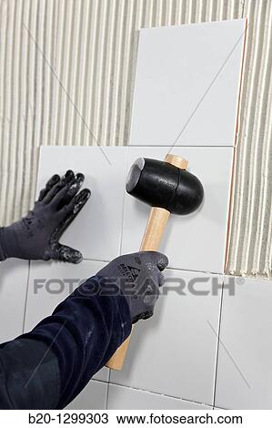 Laying tiles on glue mortar-covered wall using rubber mallet, new homes under construction, construction site View Large Photo Image Stock Image - Laying tiles on glue mortar-covered wall using rubber mallet, new homes under construction, construction site. Fotosearch