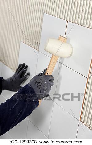 Laying tiles on glue mortar-covered wall using rubber mallet, new homes under construction, construction site View Large Photo Image Stock Photo - Laying tiles on glue mortar-covered wall using rubber mallet, new homes under construction, construction site. Fotosearch