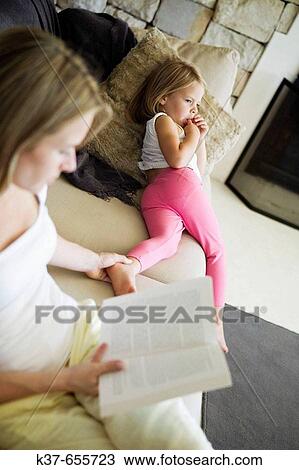 Stock Image - Lazy afternoon. 4 y/o daughter with mother on sofa in livingroom.. Fotosearch