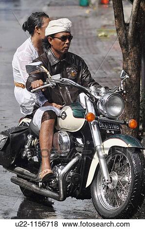 Stock Photo - Legian (Bali, Indonesia): traditional Balinese couple on an American-style motor-bike. Fotosearch