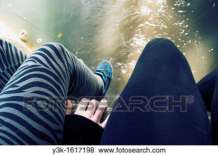 Stock Photo - Legs of two girls sitting in the bank of a river, Ayora, Valencia, Spain. Fotosearch