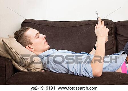 Lifestyle moment with a relaxed young adult male holding a digital tablet device in his hands View Large Photo Image Stock Image - Lifestyle moment with a relaxed young adult male holding a digital tablet device in his hands. Fotosearch
