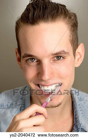 Lifestyle portrait of happy young man brushing his teeth with a pink toothbrush. View Large Photo Image Stock Image - Lifestyle portrait of happy young man brushing his teeth with a pink toothbrush.. Fotosearch