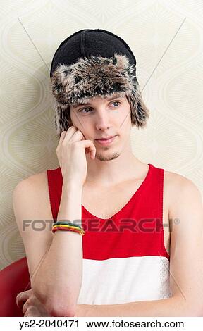 Stock Image - Lifestyle portrait of serious young man with winter hat and tank top.. Fotosearch