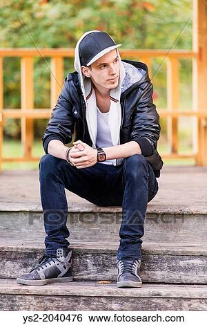 Lifestyle portrait of young man in leather jacket sitting in a park looking away. View Large Photo Image Stock Photograph - Lifestyle portrait of young man in leather jacket sitting in a park looking away.. Fotosearch
