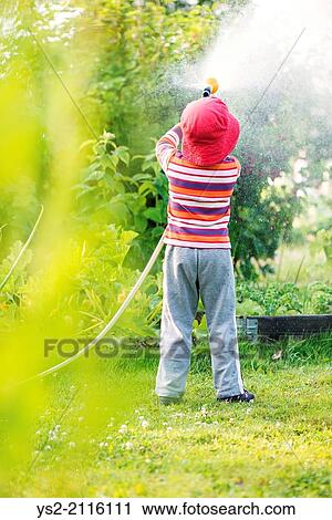 Lifestyle summer scene. Little girl watering garden plants and vegetables with sprinkler. View Large Photo Image Stock Image - Lifestyle summer scene. Little girl watering garden plants and vegetables with sprinkler.. Fotosearch