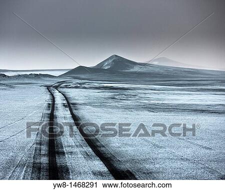 Stock Image - Light snow on ash filled landscape wth jeep tracks off road Iceland Asf fall from the Grimsvotn, volcano eruption which began on May 21, 2011. Fotosearch