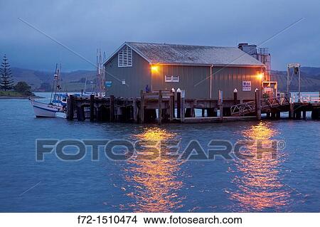 Lights Mangonui wharf reflected in water at dusk in Mangonui Harbour in Bay of Islands View Large Photo Image Picture - Lights Mangonui wharf reflected in water at dusk in Mangonui Harbour in Bay of Islands. Fotosearch