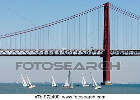 Lisbon Portugal Yachts sailing on the Tagus River with the Ponte 25 de Abril in the background View Large Photo Image Stock Image - Lisbon Portugal Yachts sailing on the Tagus River with the Ponte 25 de Abril in the background. Fotosearch
