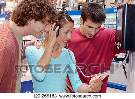 Stock Image - Listening to a CD at shopping center. Fotosearch