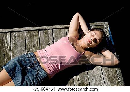 Listening to music lying on dock View Large Photo Image Stock Image - Listening to music lying on dock. Fotosearch