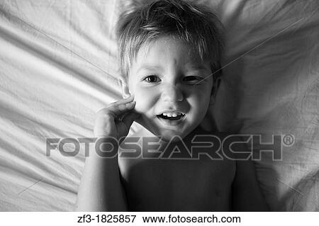 Litle boy playing with his face on the bed View Large Photo Image Stock Photo - Litle boy playing with his face on the bed. Fotosearch
