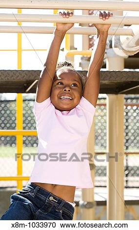 Little black girl swinging on the monkey bars in a playground View Large Photo Image Stock Image - Little black girl swinging on the monkey bars in a playground. Fotosearch