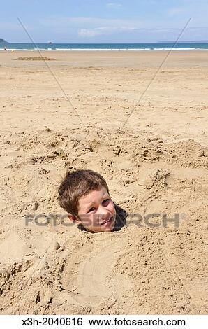 Stock Photograph - little boy buried in sand on the Kervel beach, Douarnenez, Finistere department, Brittany region, west of France, western Europe.. Fotosearch