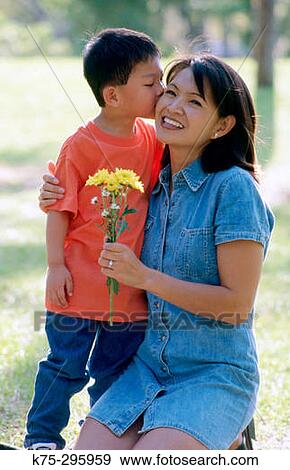 Stock Photo - little boy gives mom a kiss and flowers. Fotosearch