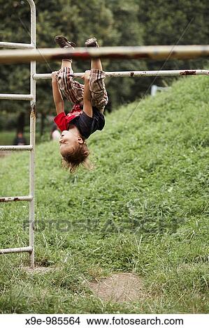Little boy hanging upside down from the ladder in the park View Large Photo Image Picture - Little boy hanging upside down from the ladder in the park. Fotosearch