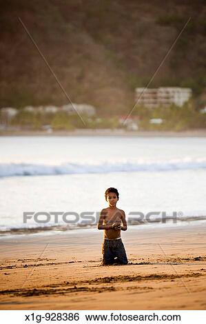 Little boy kneeling in the sand on the shore of San Juan del Sur, Nicaragua View Large Photo Image Stock Photograph - Little boy kneeling in the sand on the shore of San Juan del Sur, Nicaragua. Fotosearch