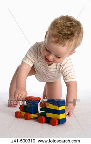 Little boy playing with a wooden train View Large Photo Image Stock Image - Little boy playing with a wooden train. Fotosearch