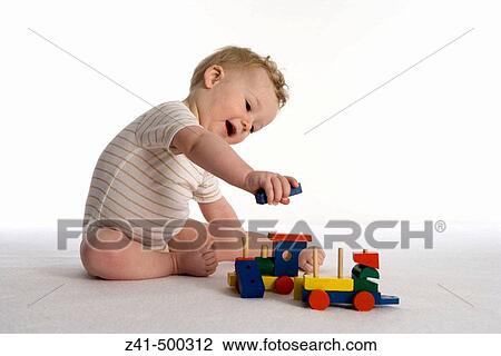 Stock Image - Little boy playing with a wooden train. Fotosearch