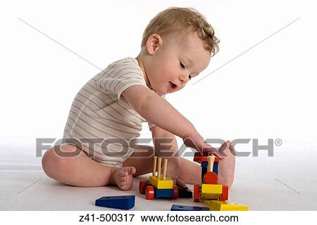 Little boy playing with a wooden train View Large Photo Image Stock Photo - Little boy playing with a wooden train. Fotosearch