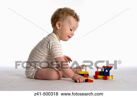 Little boy playing with a wooden train View Large Photo Image Stock Photo - Little boy playing with a wooden train. Fotosearch