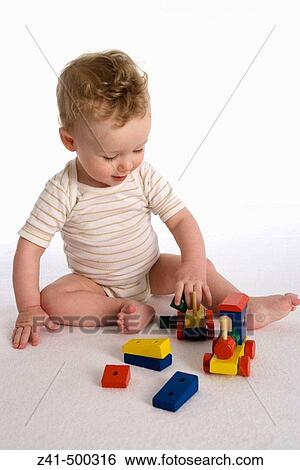 Stock Photograph - Little boy playing with a wooden train. Fotosearch
