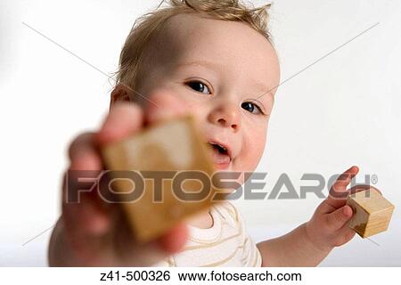 Stock Photograph - Little boy reaching out with a wooden brick. Fotosearch