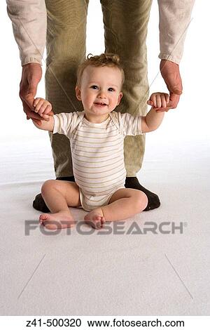 Stock Image - Little boy sitting against his father's legs. Fotosearch