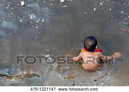 Stock Photo - Little boy sitting in polluted water.. Fotosearch