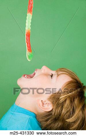 Stock Image - Little boy trying to catch sugar snake with his mouth. Fotosearch