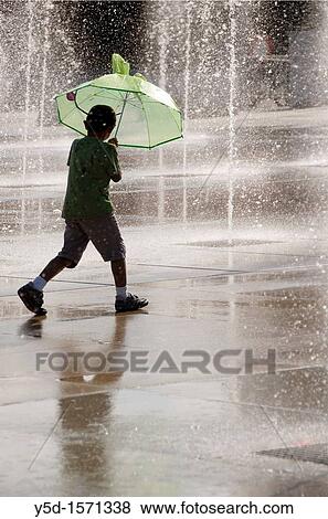 little boy walking with umbrella in water drops falling from the fountains around, front of Palace of Nations, Geneva, Switzerland View Large Photo Image Stock Photo - little boy walking with umbrella in water drops falling from the fountains around, front of Palace of Nations, Geneva, Switzerland. Fotosearch