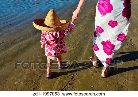 Little child with a sombrero hat holds his mother hands while walking on the beach. View Large Photo Image Stock Image - Little child with a sombrero hat holds his mother hands while walking on the beach.. Fotosearch