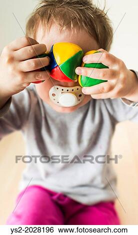 Little girl, 3 years old, having fun and hiding behind colorful balls. View Large Photo Image Stock Photograph - Little girl, 3 years old, having fun and hiding behind colorful balls.. Fotosearch