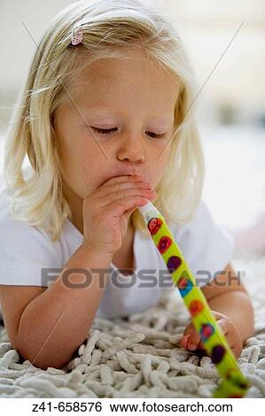 Stock Photograph - Little girl blowing a paper whistle. Fotosearch