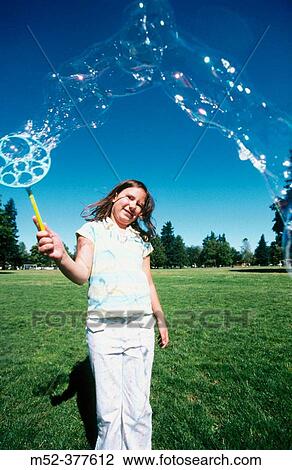 Stock Image - Little girl blowing bubbles. Fotosearch