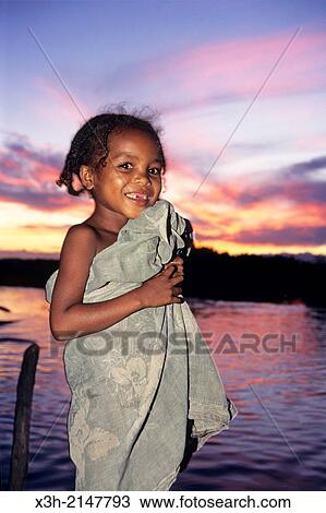 Stock Image - little girl by the Pangalanes Canal at sunset, Madagascar, Indian Ocean, Southeast Africa.. Fotosearch