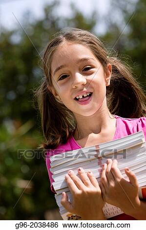 Stock Photograph - Little girl carries a lot of books.. Fotosearch