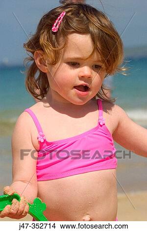 Picture - Little girl carrying a bucket in the beach. Fotosearch