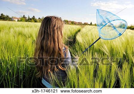 Stock Image - little girl catching butterfly in a barley field, commune of Senantes, Eure-et-Loire department, Centre region, France, Europe. Fotosearch