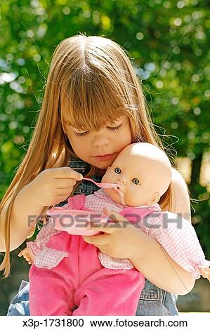 Little girl feeding a doll View Large Photo Image Stock Image - Little girl feeding a doll. Fotosearch