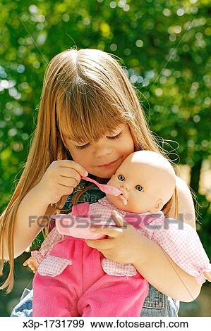 Stock Photo - Little girl feeding a doll. Fotosearch