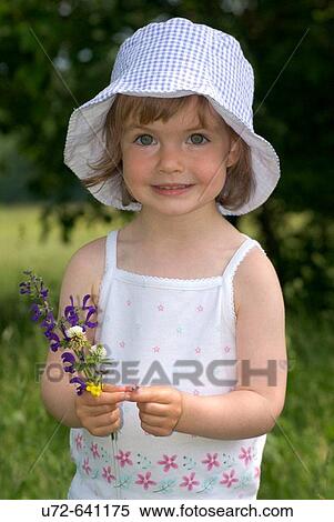 Stock Photography - Little Girl Holding Flowers in a Meadow. Fotosearch