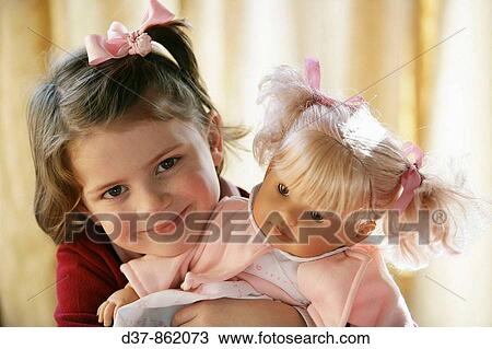 Little girl holding her doll with affection View Large Photo Image Stock Image - Little girl holding her doll with affection. Fotosearch