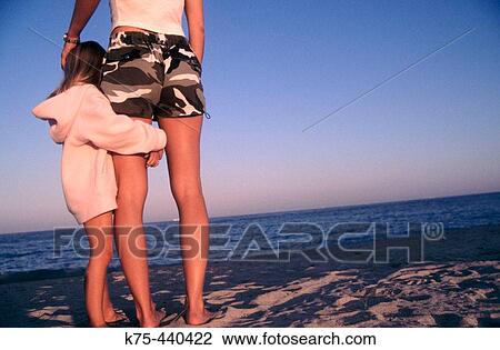 Stock Image - Little girl hugs mom at beach. Fotosearch